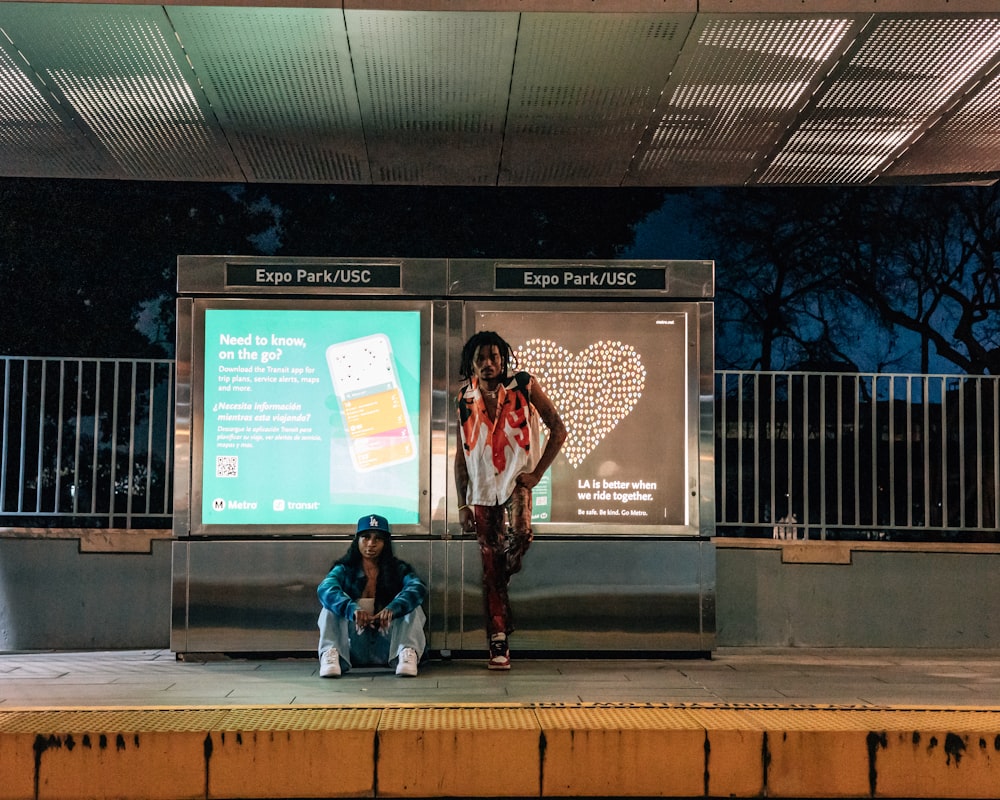 a couple of people that are standing in front of a sign