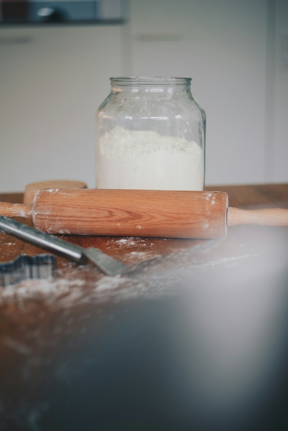 a wooden table topped with a cookie cutter and a jar of flour