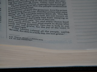A close-up view of a page from a book containing printed text. The text discusses a religious or historical narrative, mentioning Nehemiah, the Levites, and the importance of a holy day. The page is open with some lines highlighted or bolded for emphasis.