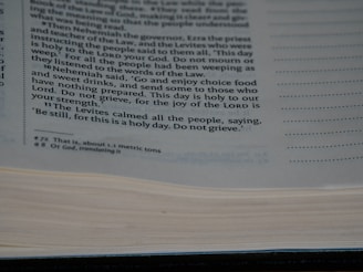 A close-up view of a page from a book containing printed text. The text discusses a religious or historical narrative, mentioning Nehemiah, the Levites, and the importance of a holy day. The page is open with some lines highlighted or bolded for emphasis.