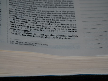 A close-up view of a page from a book containing printed text. The text discusses a religious or historical narrative, mentioning Nehemiah, the Levites, and the importance of a holy day. The page is open with some lines highlighted or bolded for emphasis.