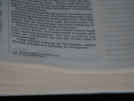 A close-up view of a page from a book containing printed text. The text discusses a religious or historical narrative, mentioning Nehemiah, the Levites, and the importance of a holy day. The page is open with some lines highlighted or bolded for emphasis.