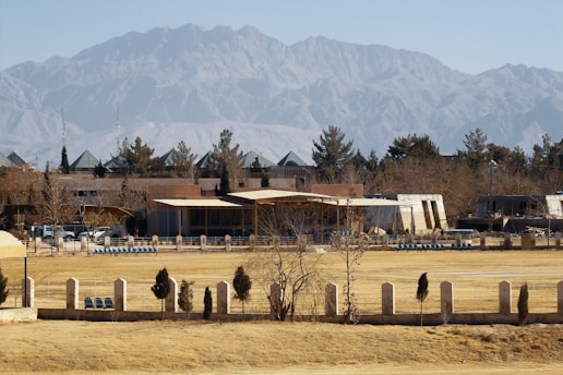 a field with a building and mountains in the background