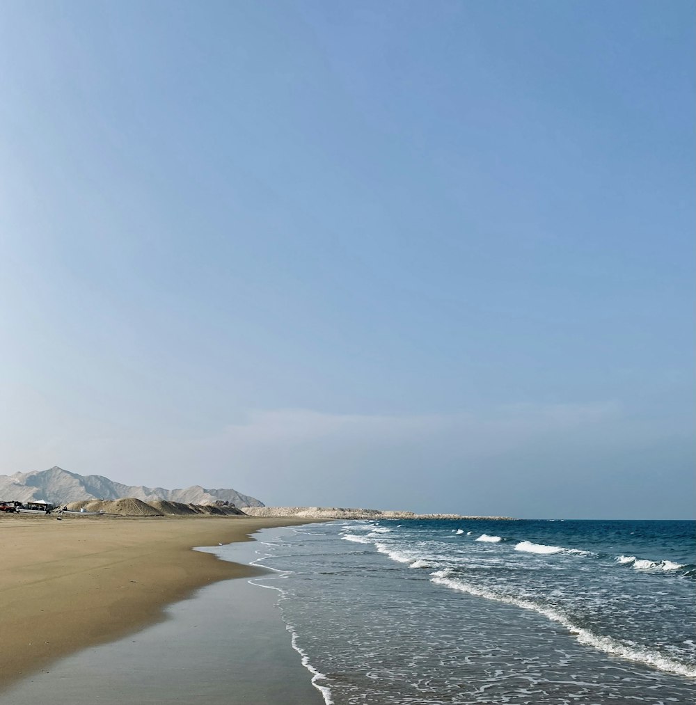 a sandy beach with waves coming in to the shore