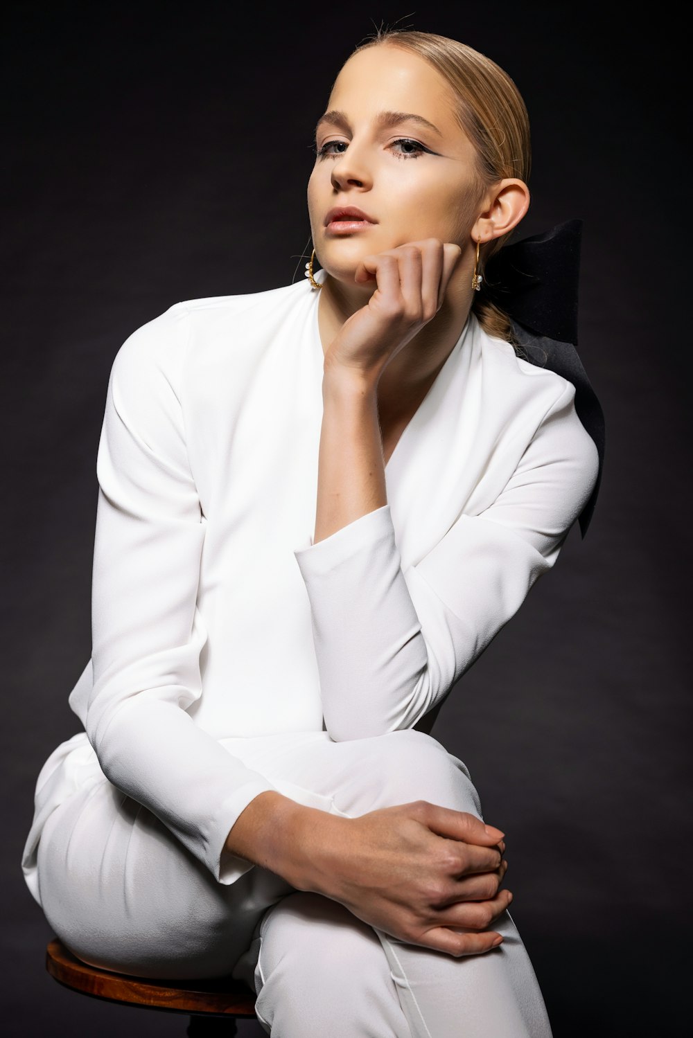 a woman sitting on a stool with her hand on her chin