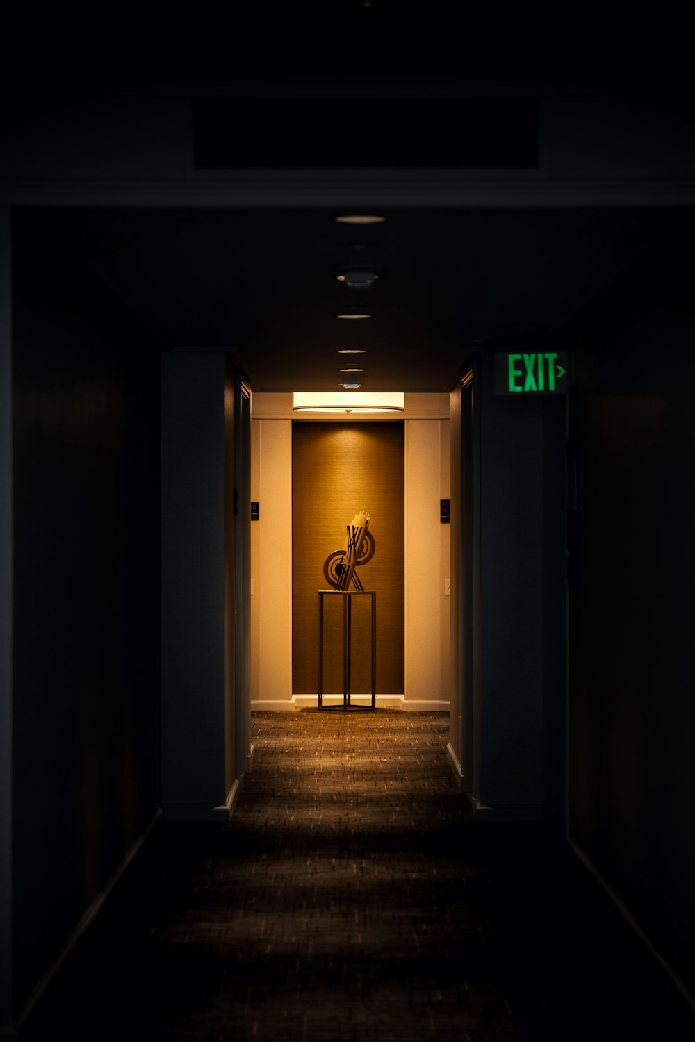 a dark hallway with a exit sign on the wall