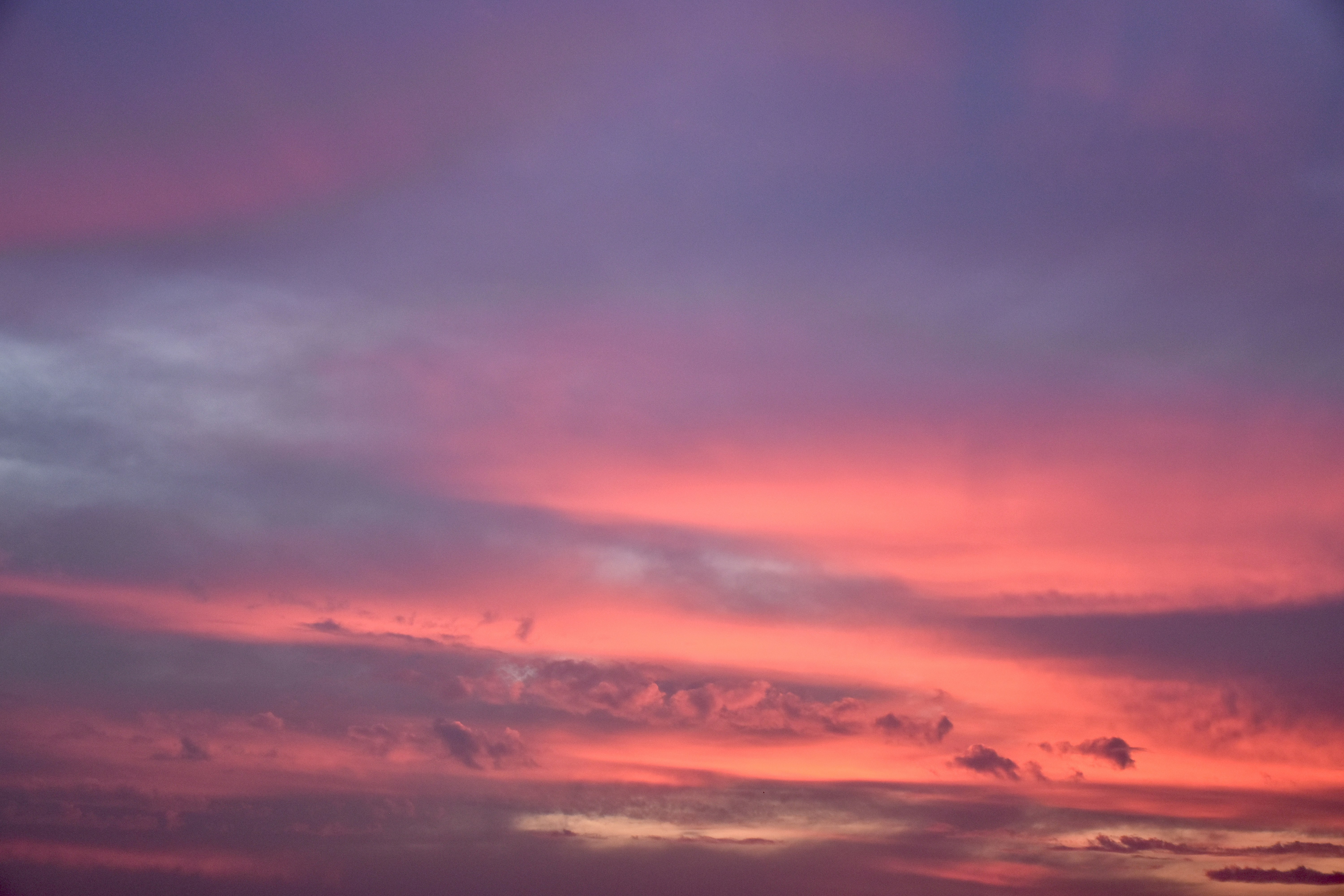 a plane flying in the sky at sunset