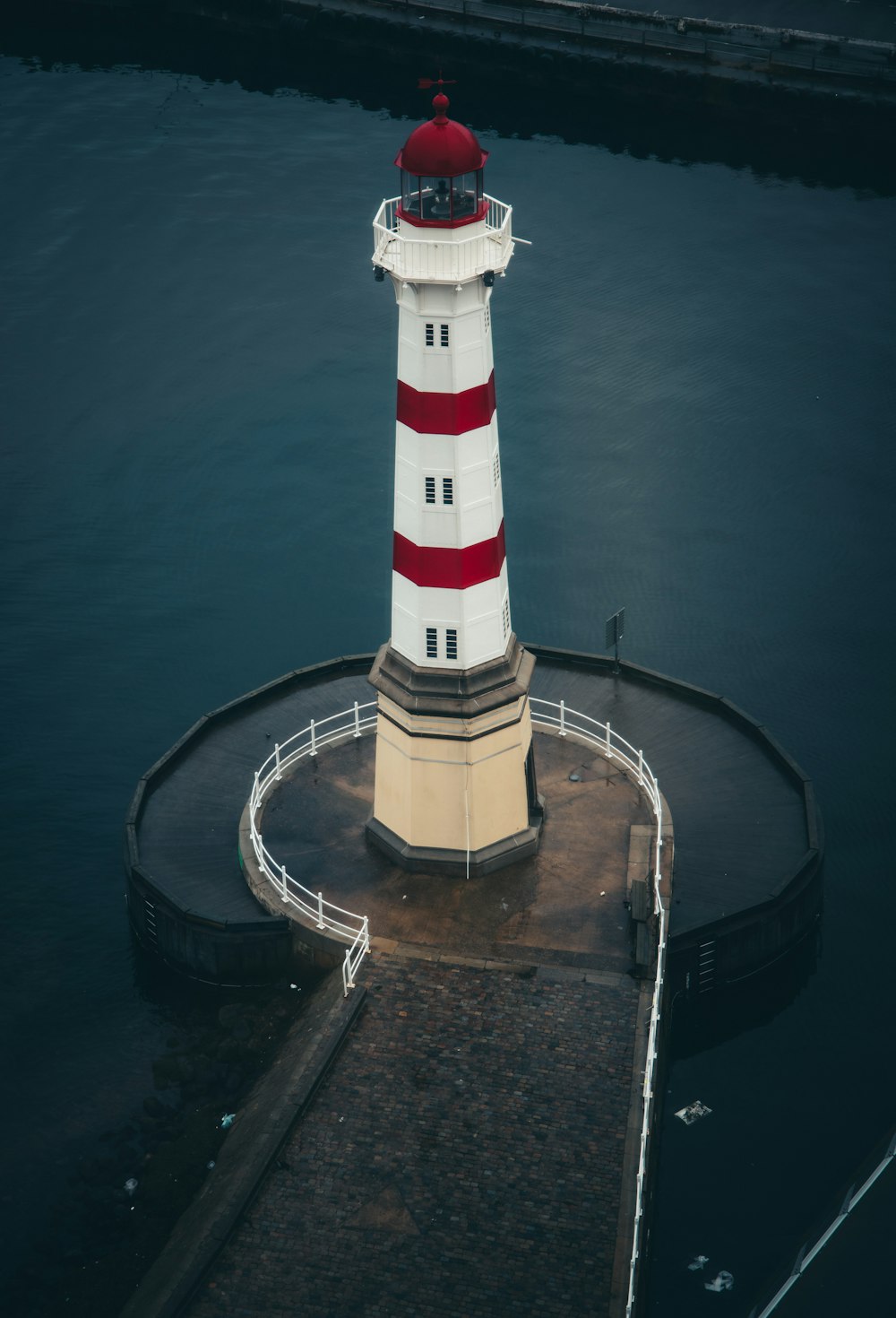 a red and white lighthouse sitting on top of a pier