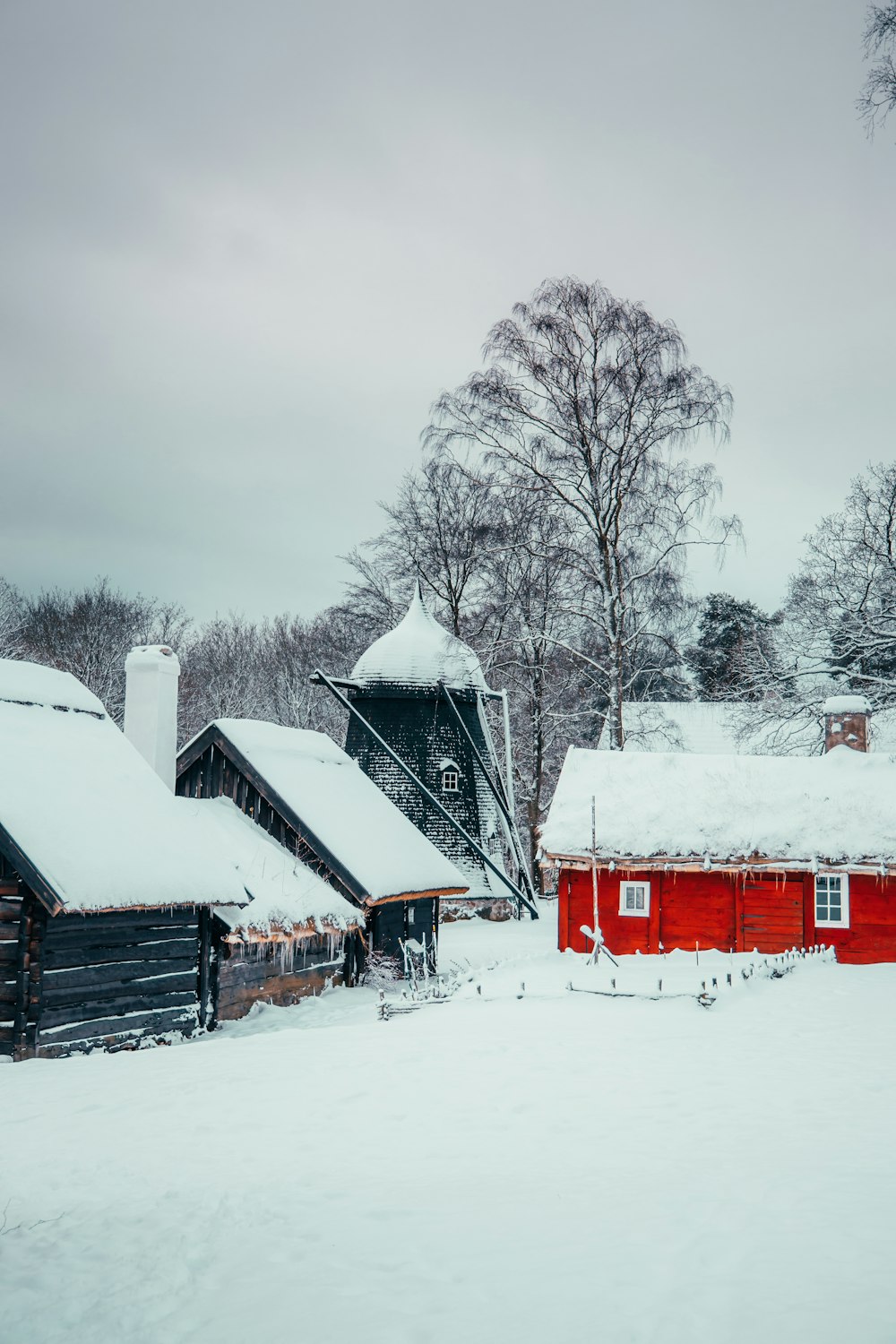 a snow covered field with a house and trees in the background