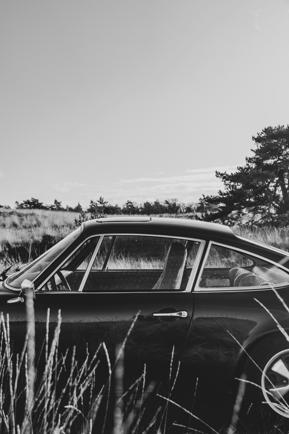 uma foto em preto e branco de um carro em um campo
