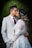 a bride and groom kissing in front of a dark background