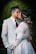 a bride and groom kissing in front of a dark background