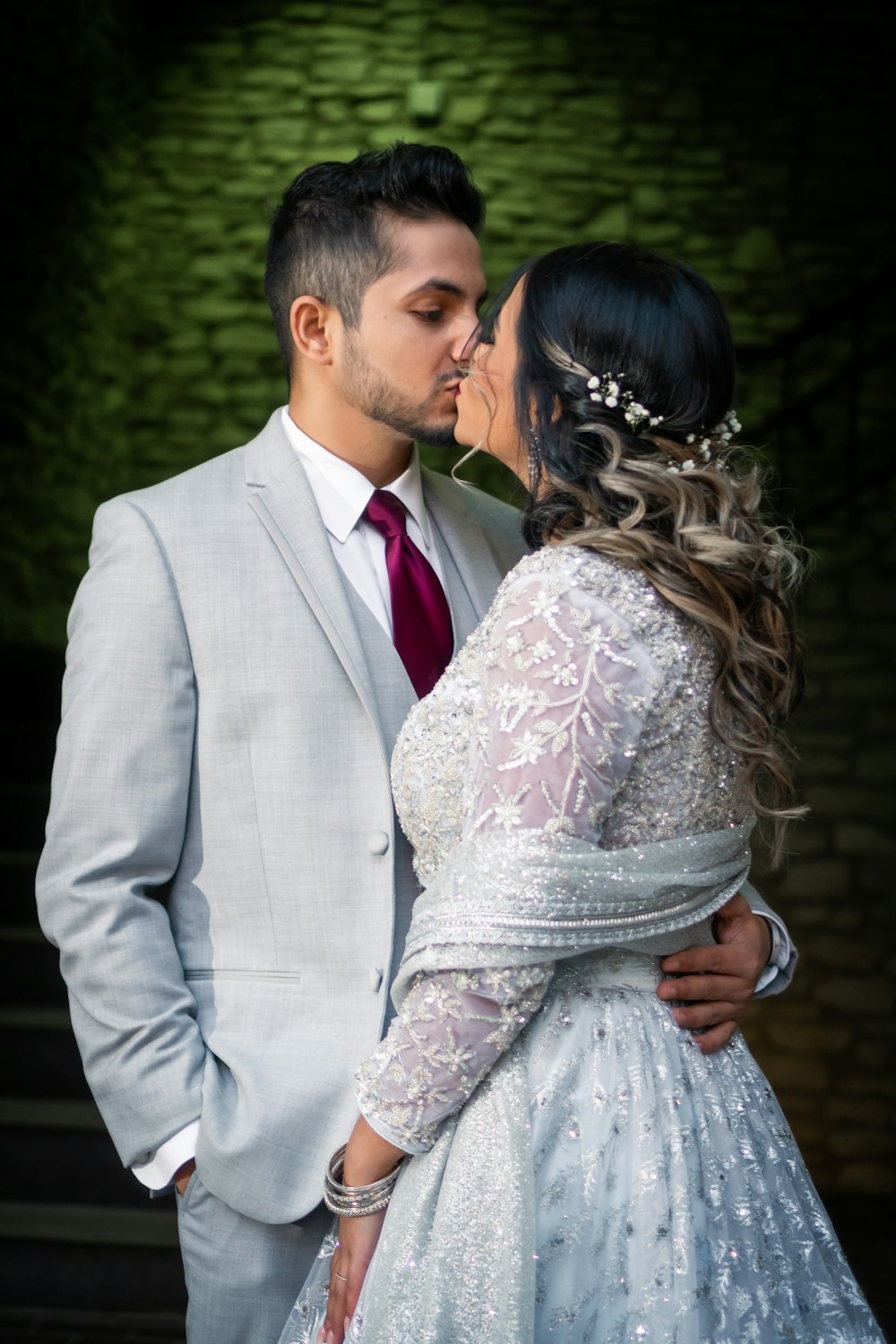 a bride and groom kissing in front of a dark background