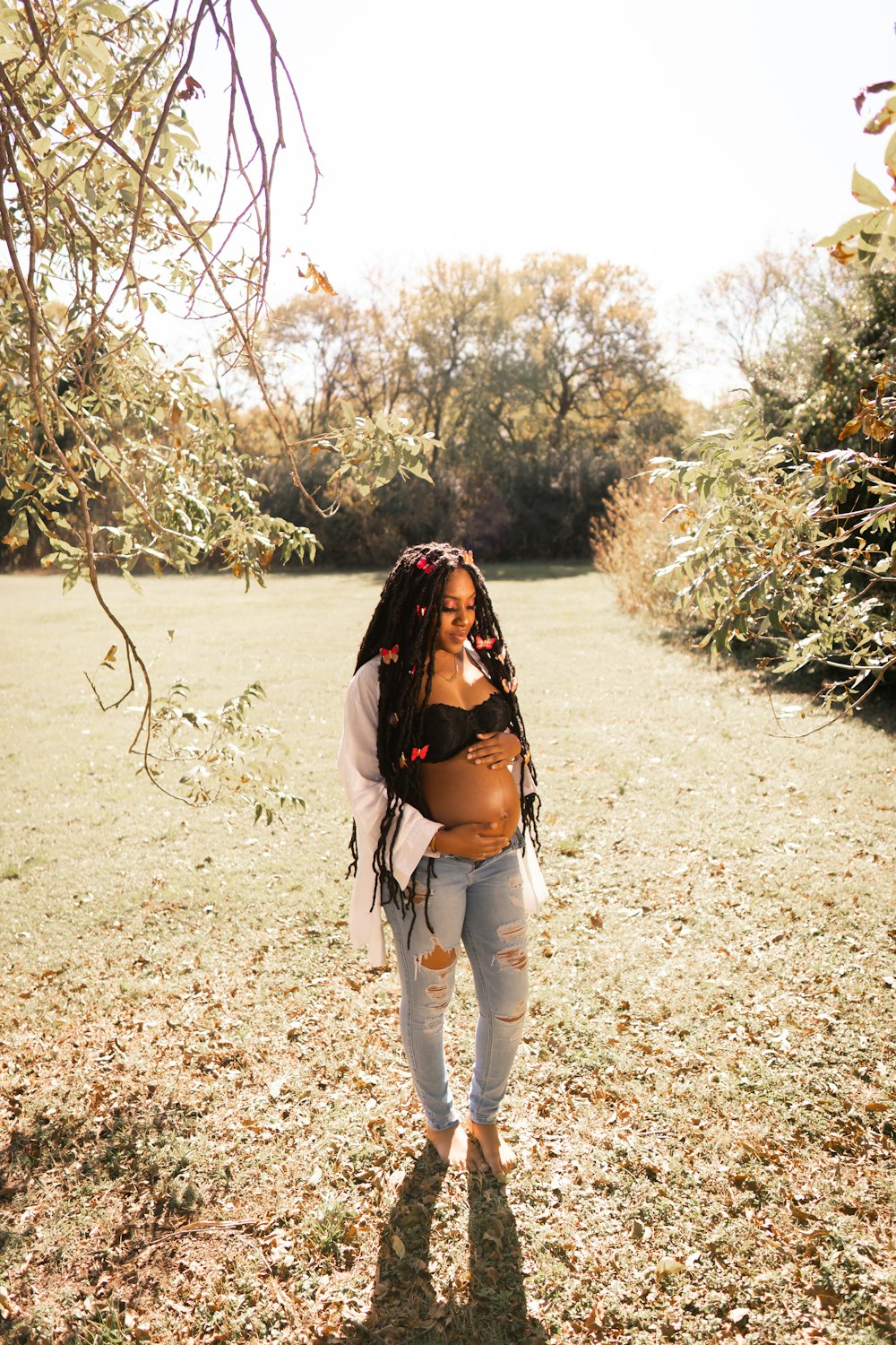 a woman standing in a field with trees in the background