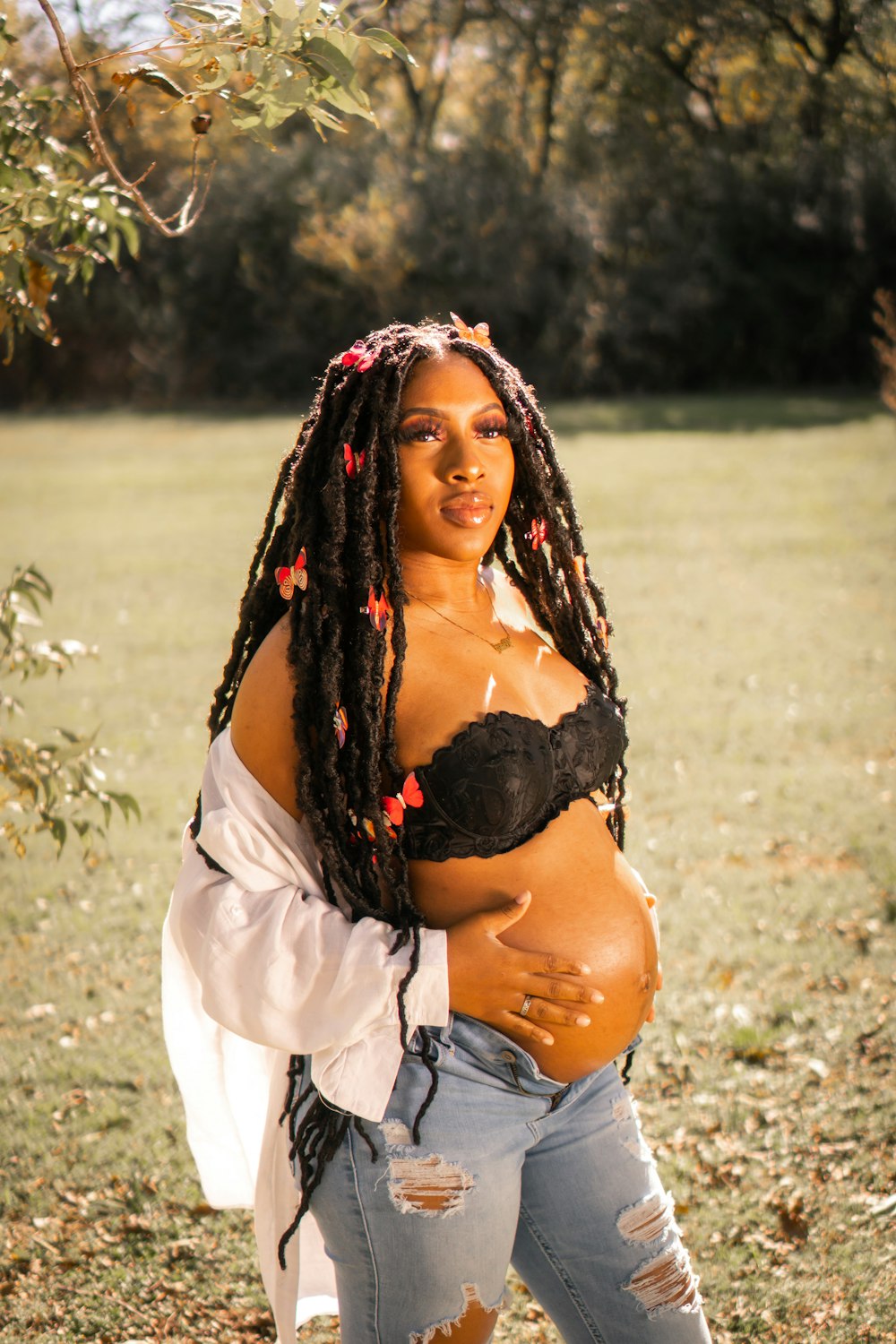 a pregnant woman in ripped jeans and a black bra