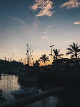 A navy blue and gold-themed postcard featuring a peaceful mariner's harbor at dusk.