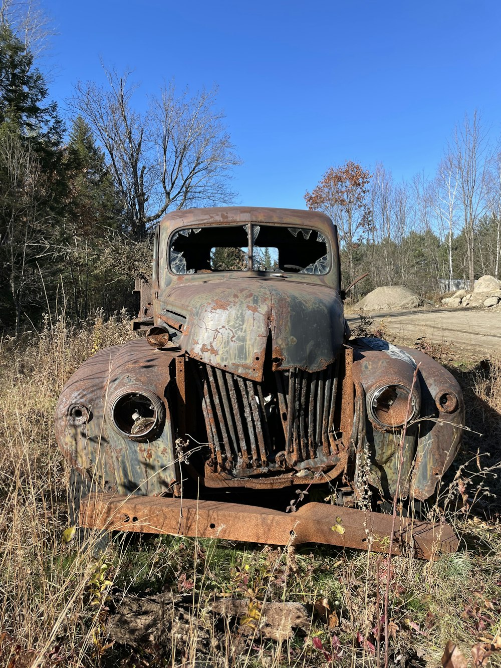 an old rusted out truck sitting in a field