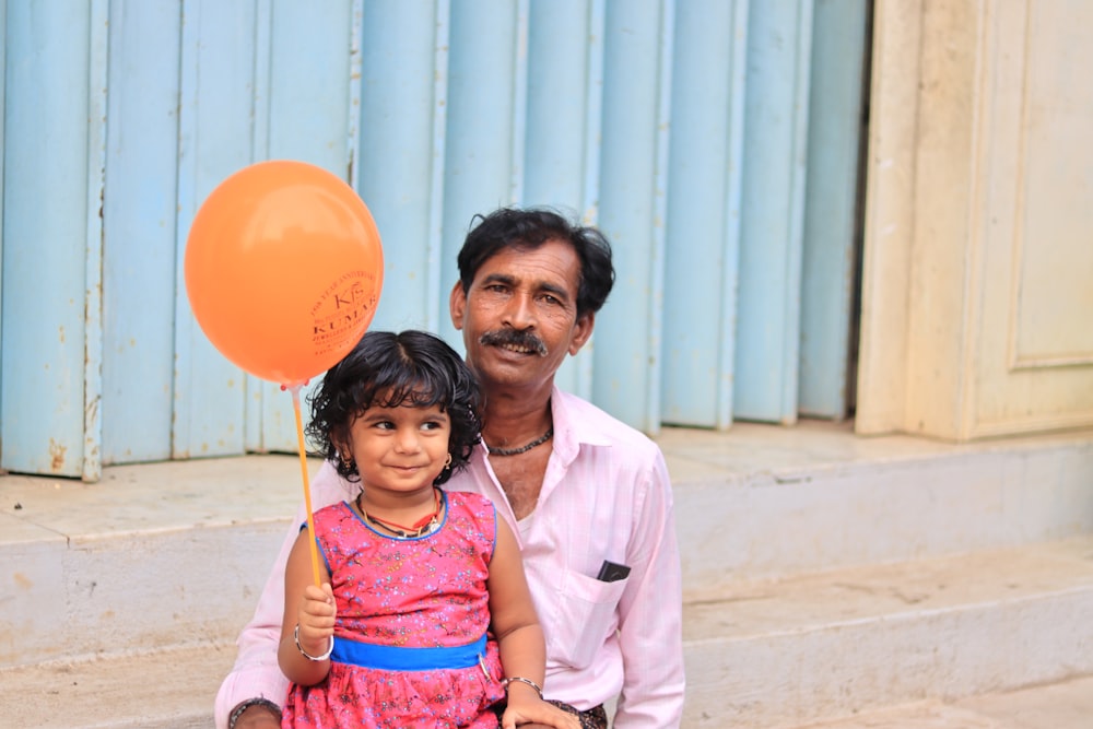 a man and a little girl holding a balloon