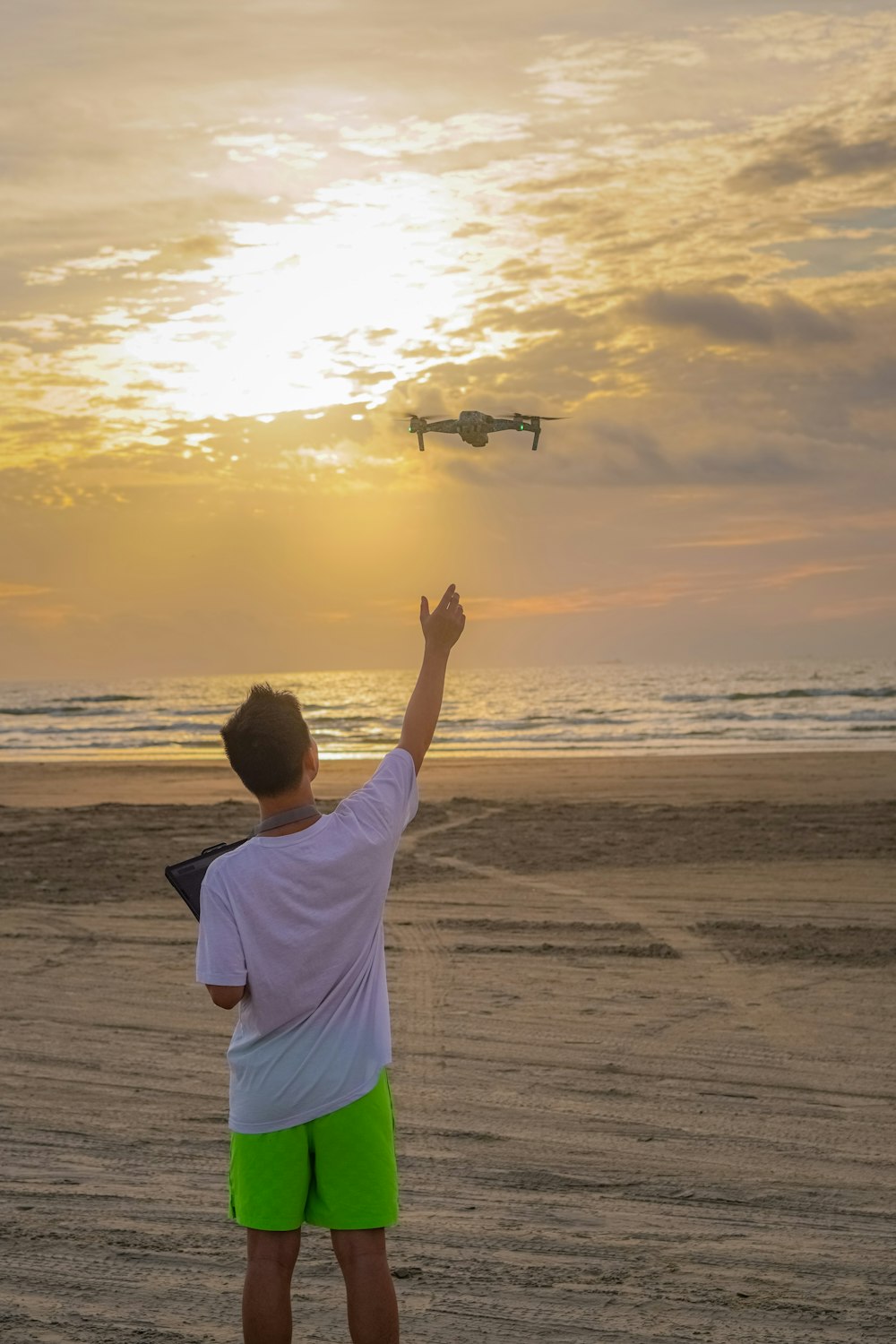 a man flying a kite on the beach at sunset