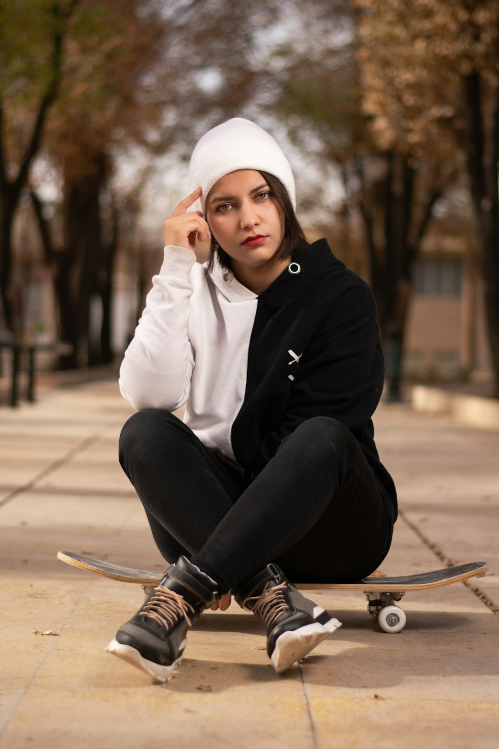 a woman sitting on a skateboard on a sidewalk