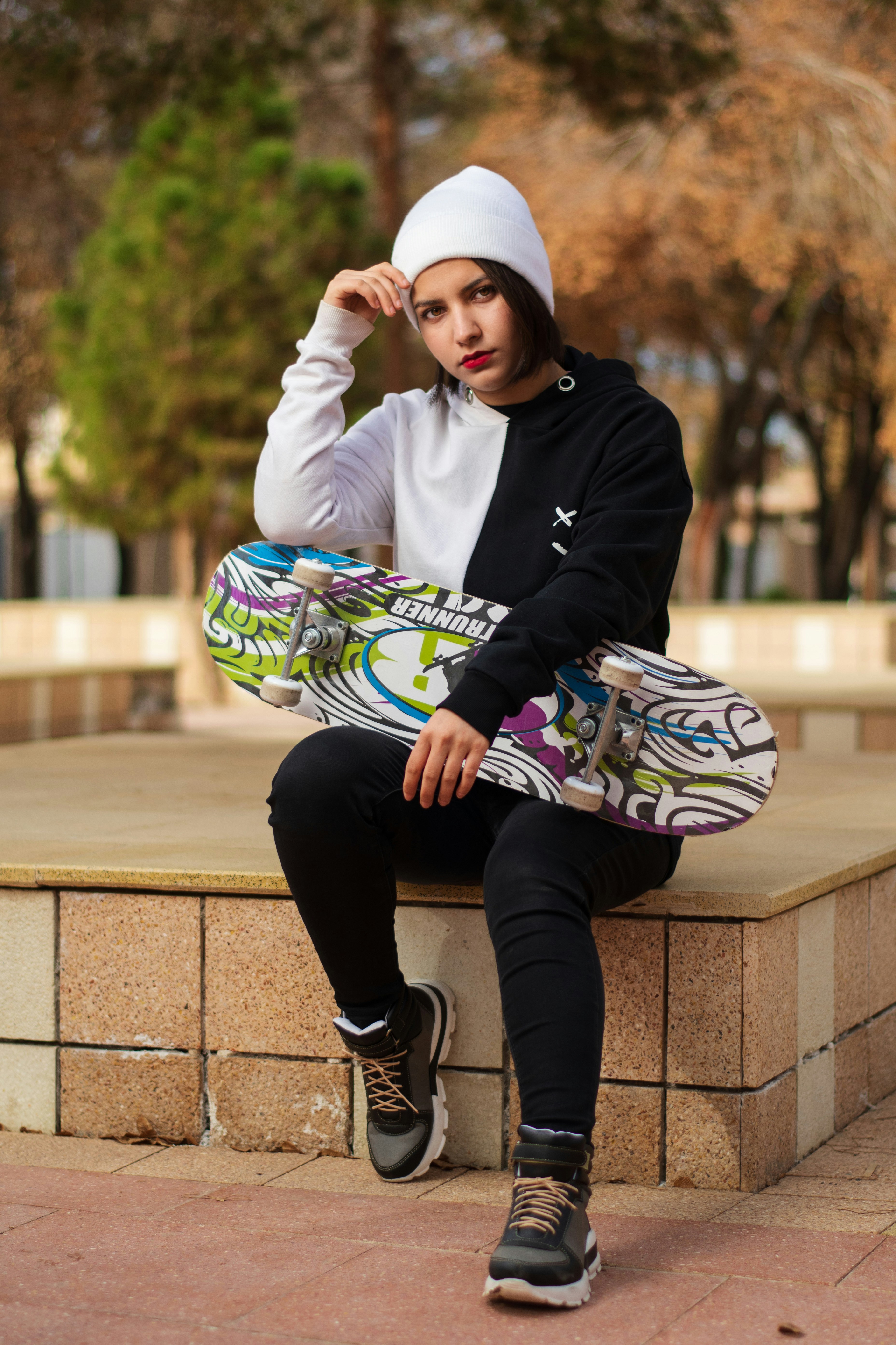 Une femme assise sur un rebord avec une planche à roulettes
