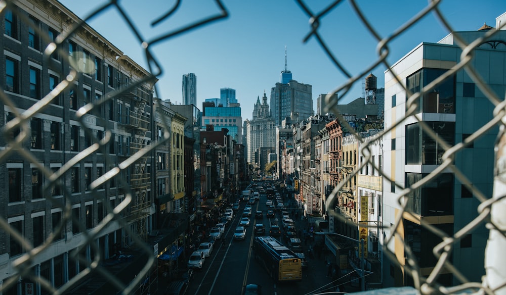 a view of a city street through a chain link fence