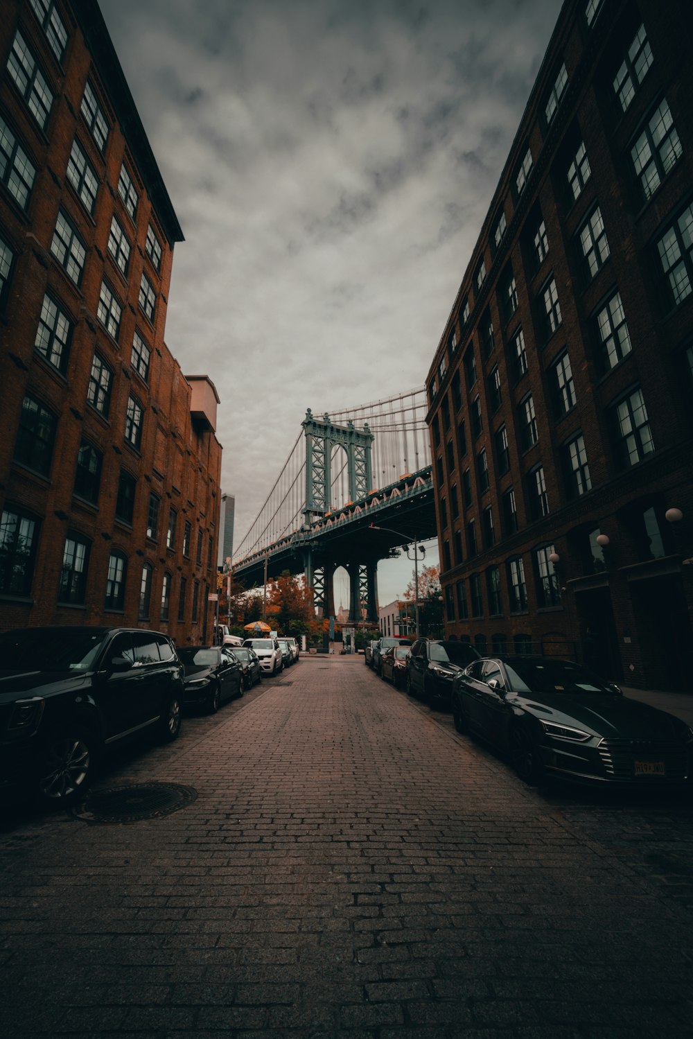 a street with cars parked in front of a bridge