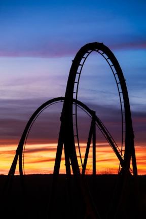 a roller coaster at sunset with the sky in the background