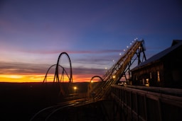 a roller coaster at sunset with the sky in the background