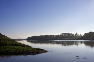 A peaceful riverside scene in Assam with light blue and green hues reflecting the site’s theme colors.