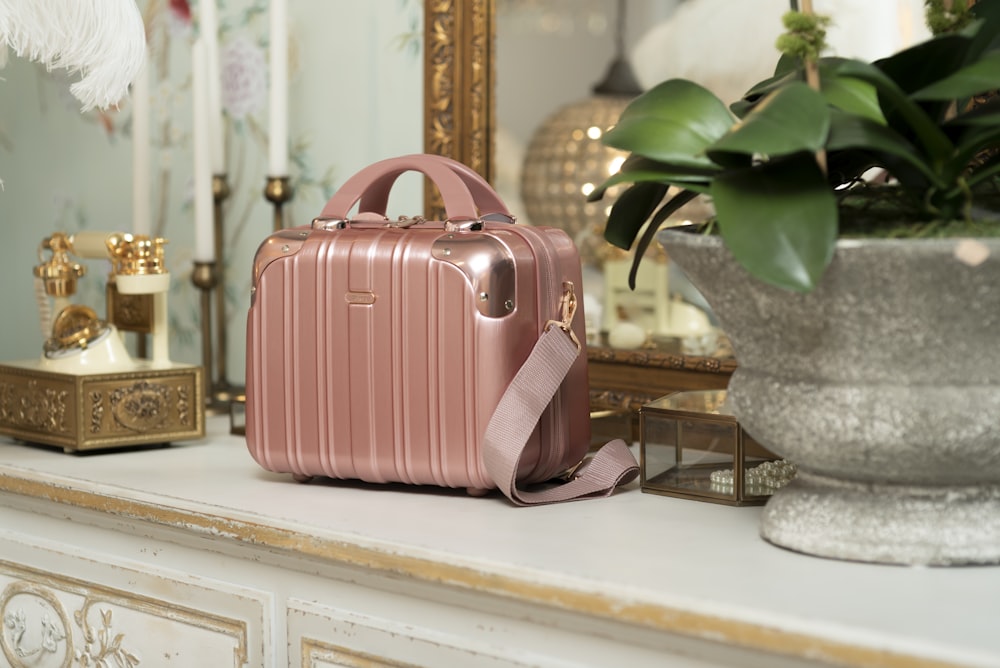 a pink suitcase sitting on top of a white mantle
