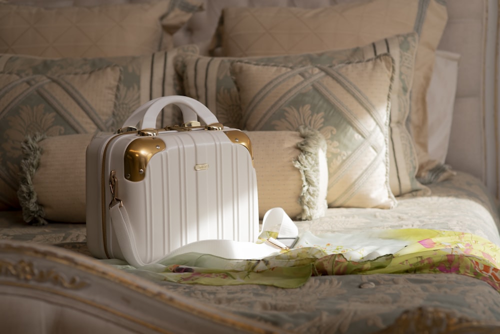 a white suitcase sitting on top of a bed