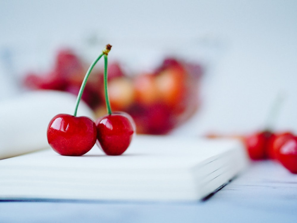a close up of two cherries on a book