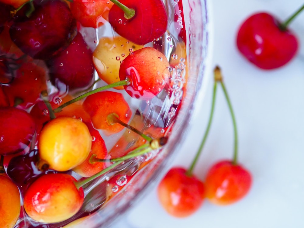 a glass bowl filled with cherries on top of a table