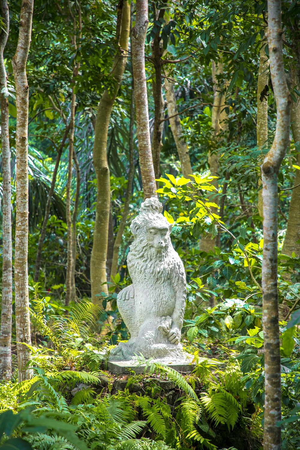 a statue of a lion in the middle of a forest