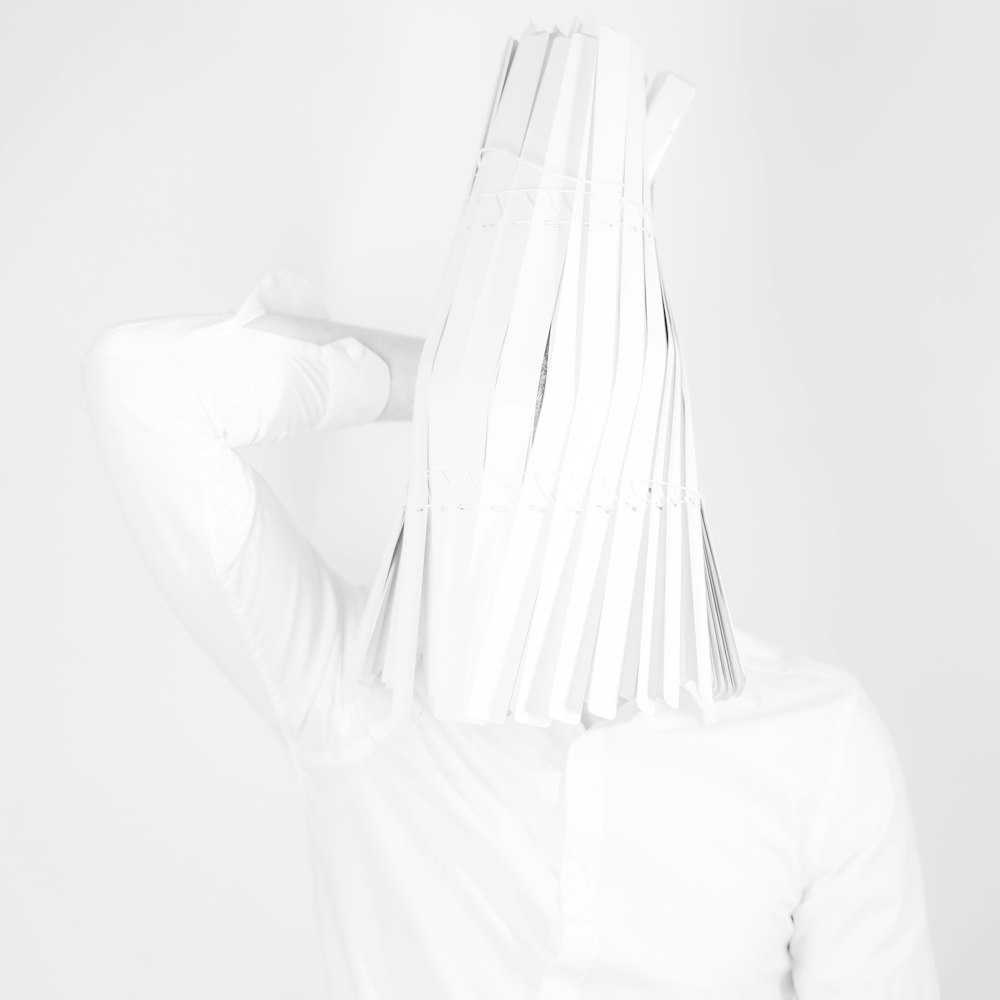 白いシャツを着た女性が手で顔を覆っている