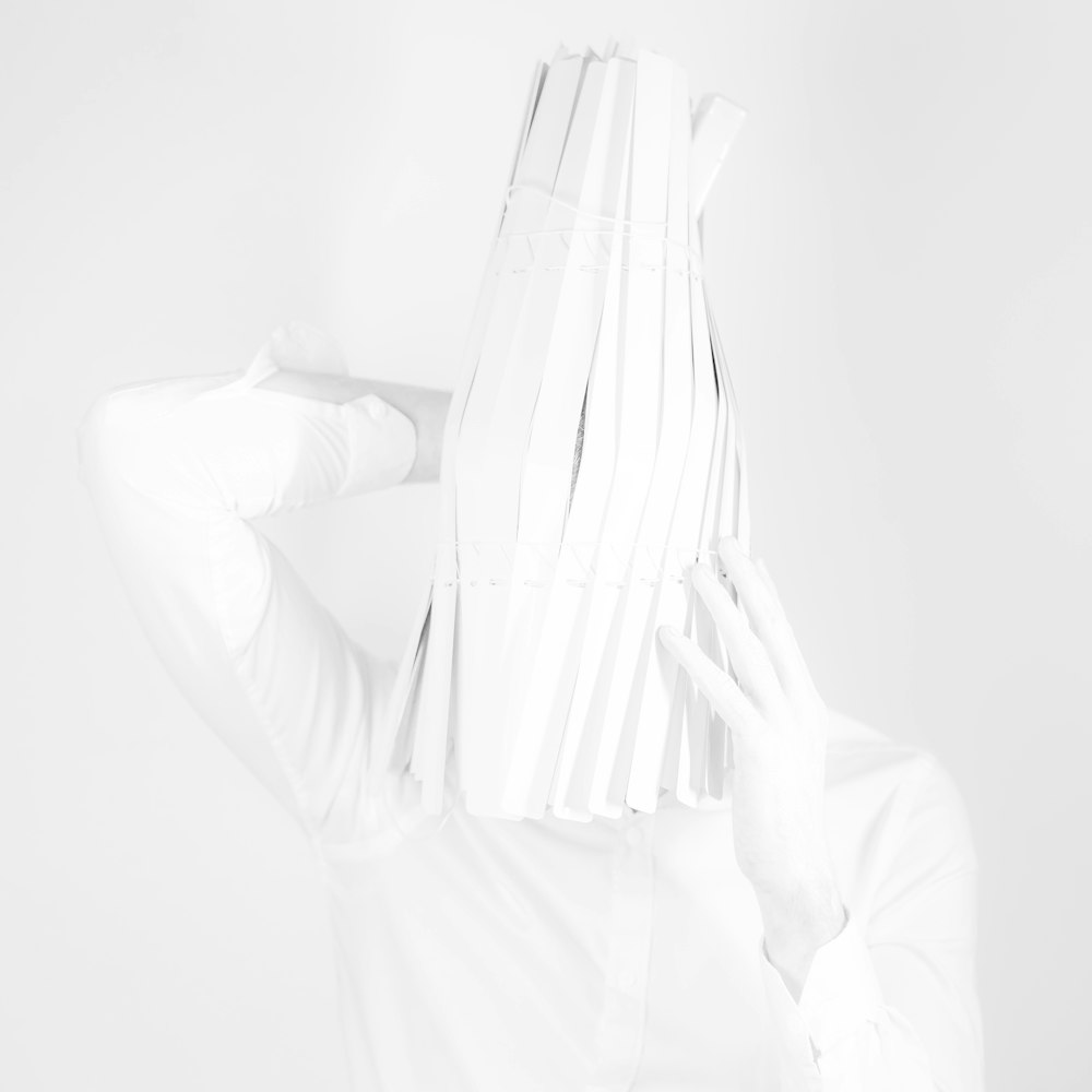 a woman in a white shirt is covering her face with her hands