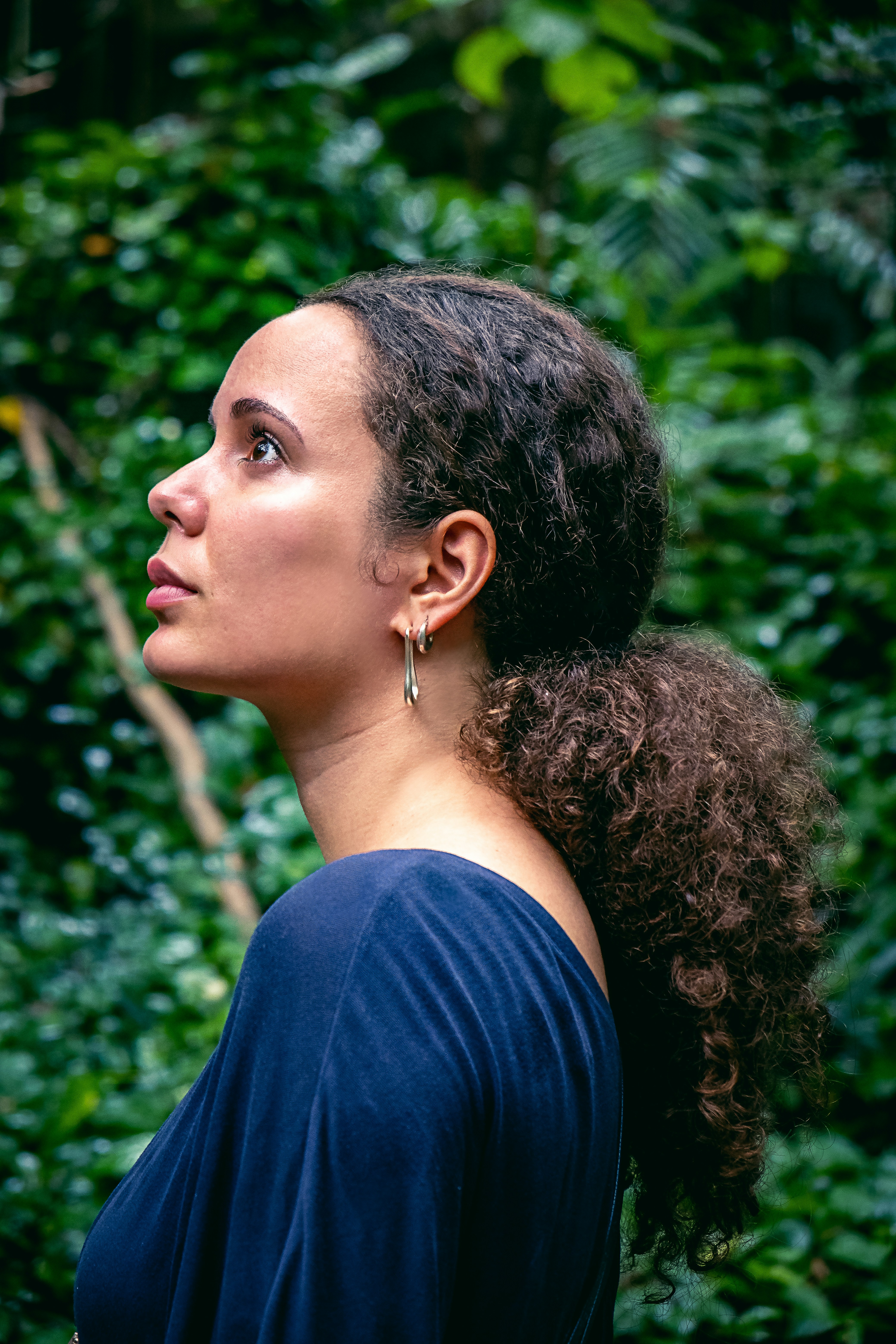 a woman standing in front of a lush green forest