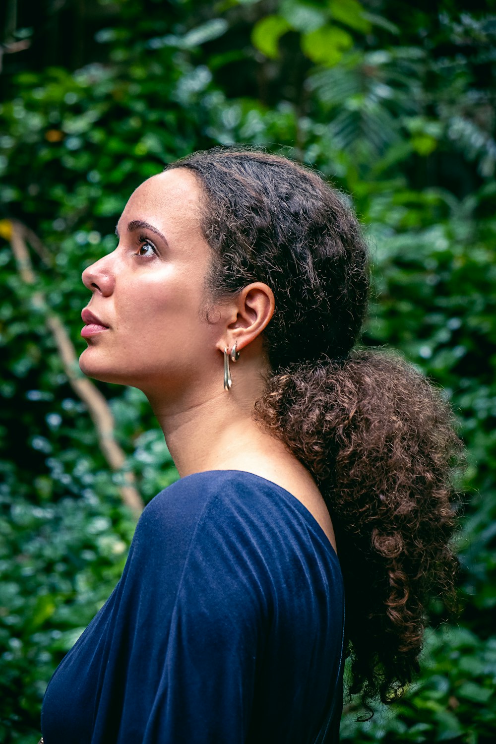 uma mulher em pé na frente de uma floresta verde exuberante