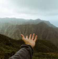 a hand reaching out towards a mountain range