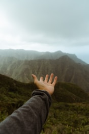 a hand reaching out towards a mountain range