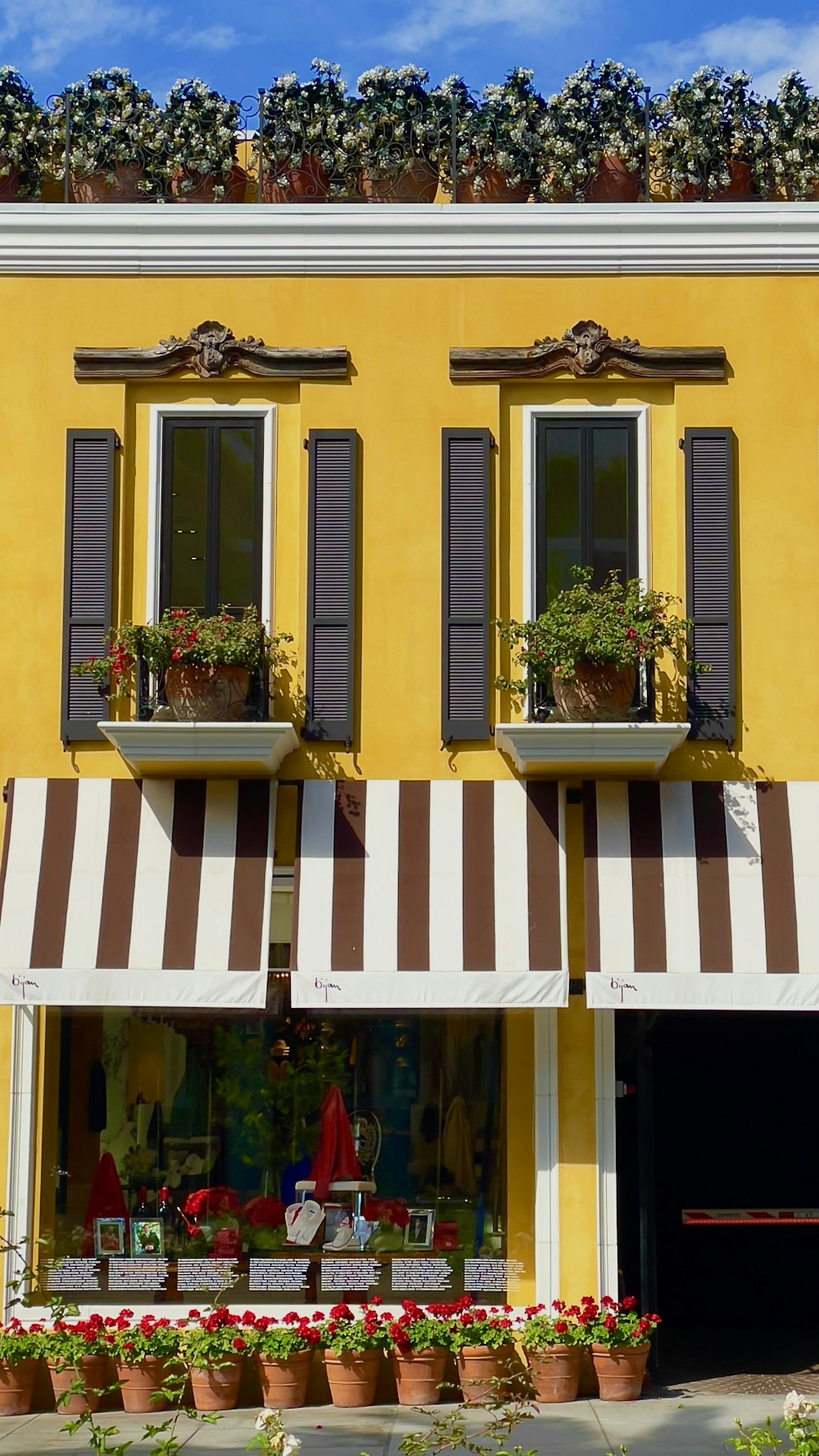 a yellow building with brown and white striped awnings