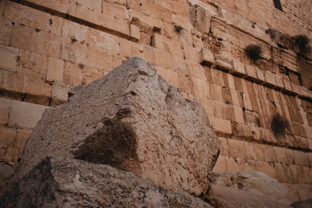 a large rock sitting in front of a tall brick building