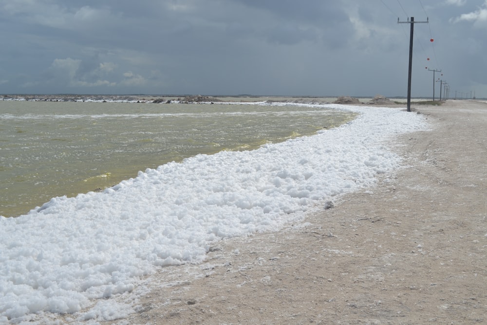 a sandy beach next to the ocean under a cloudy sky