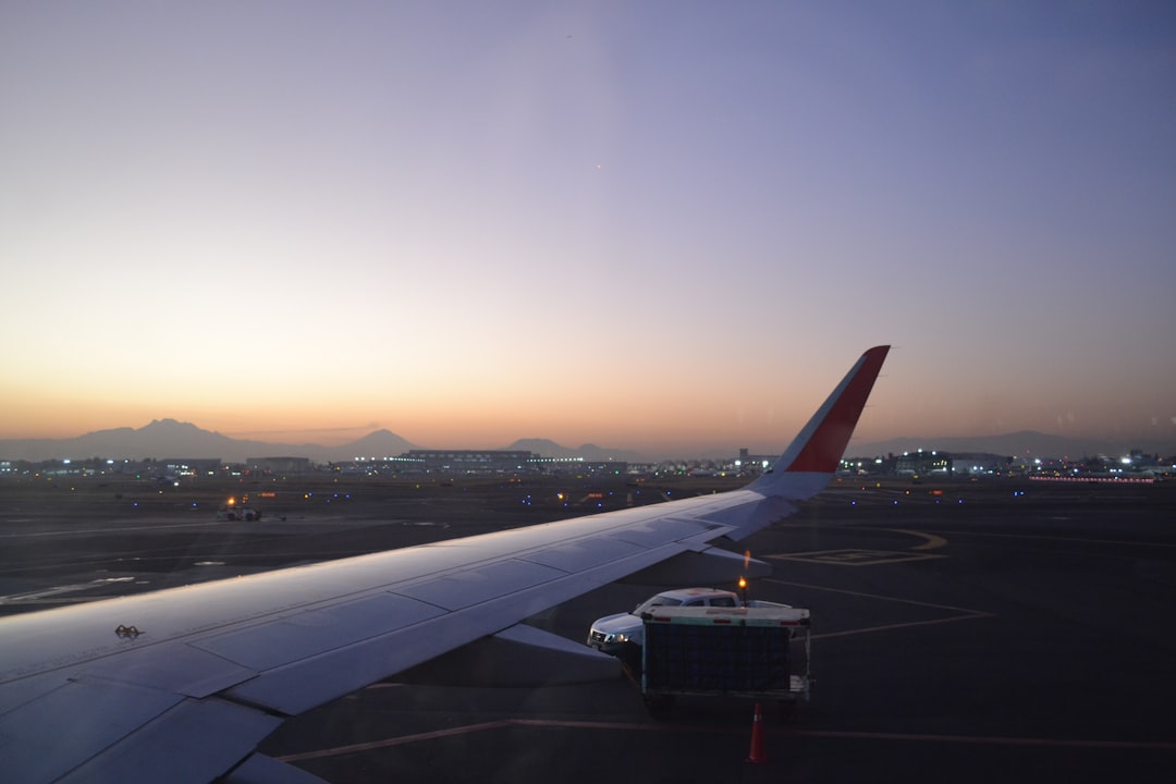 an airplane wing with the sun setting in the background,