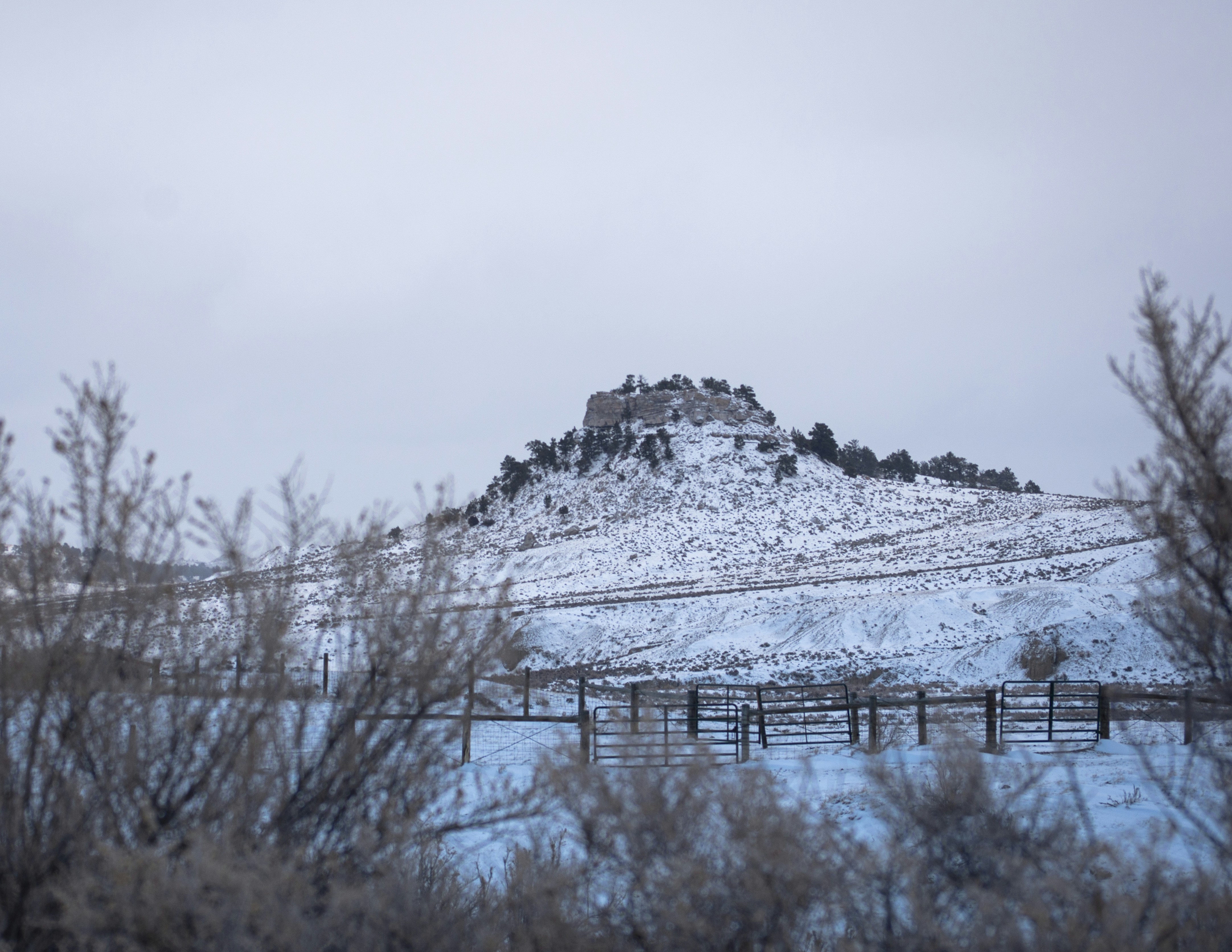 a snow covered mountain with a fence in the foreground