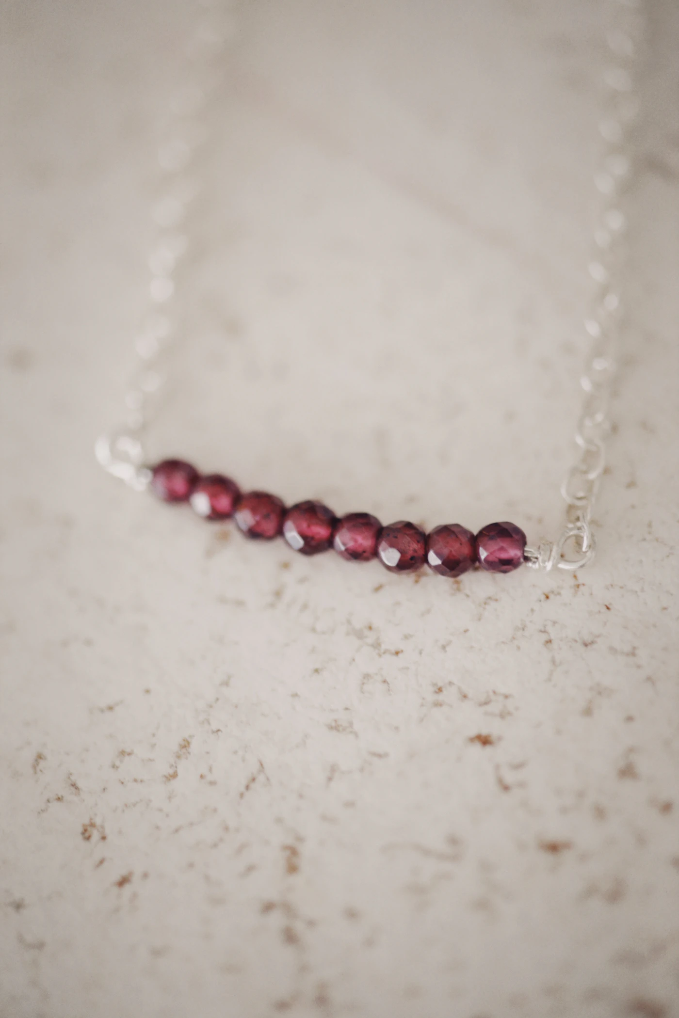 Strand of polished red garnet beads laid out on a white surface