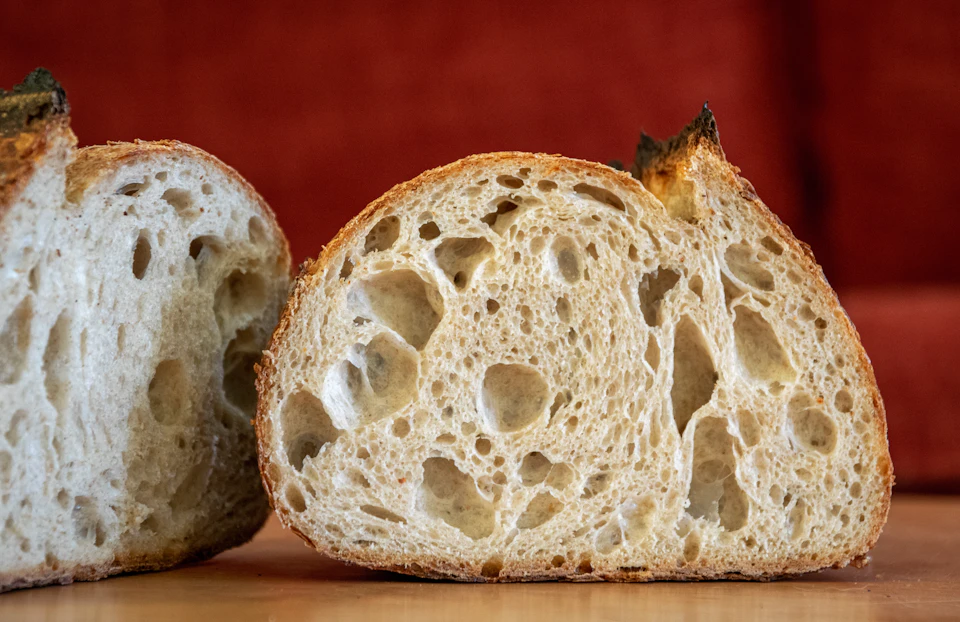 Two slices of bread with light brown crusts rest on a wooden table