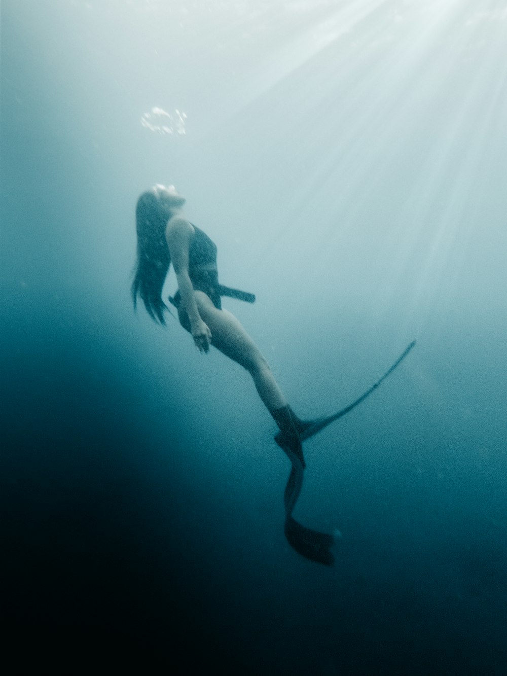 a woman in a wet suit diving in the ocean