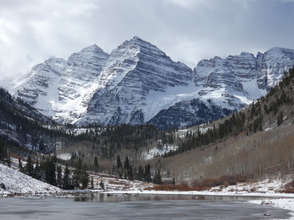 a snowy mountain range with a lake in the foreground